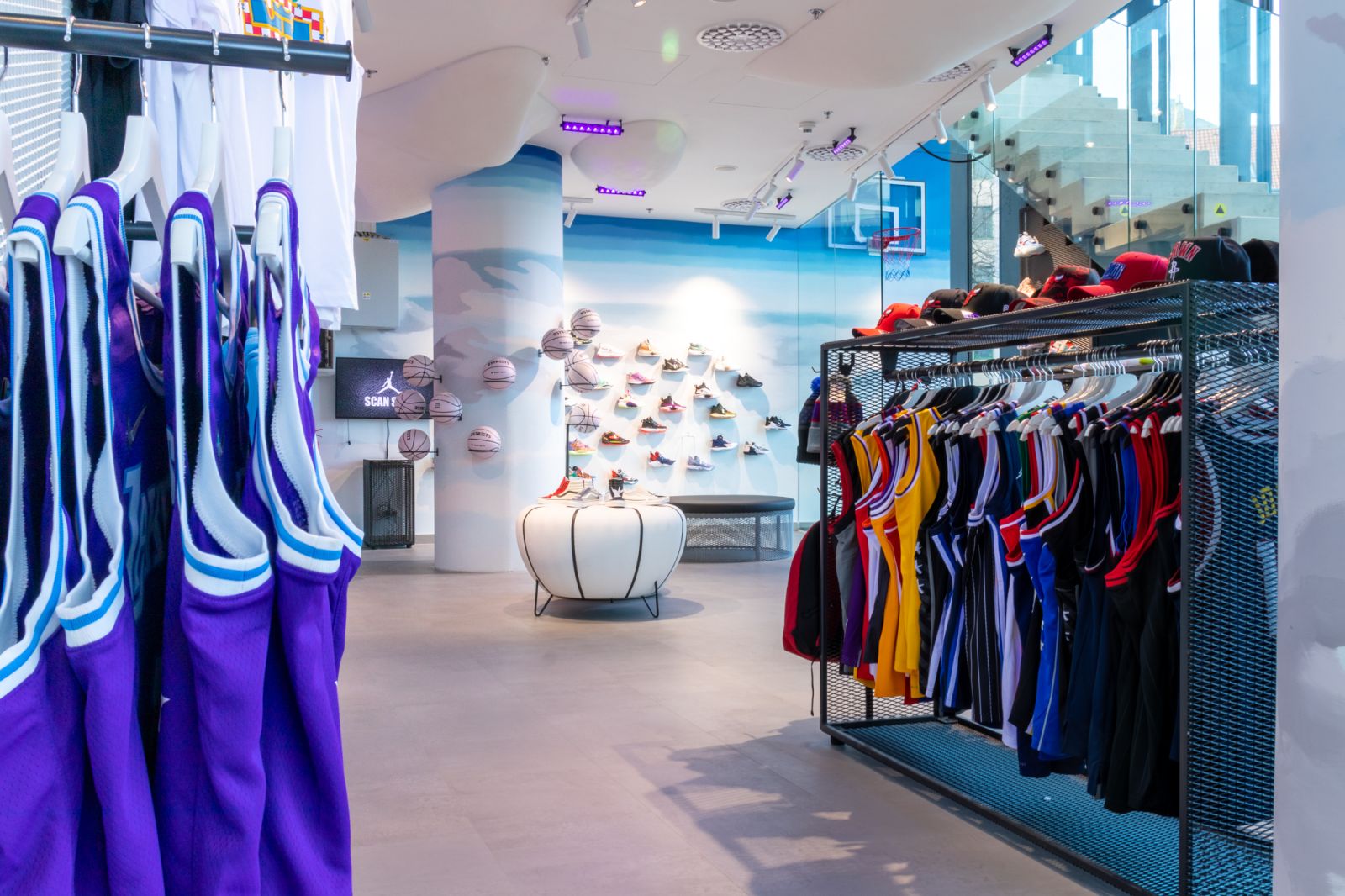 Moderner Streetball-Store mit Basketball-Trikots, Sneakers und Caps, stilvoll präsentiert in einem urbanen Design mit Basketball-Elementen und Wanddekoration.